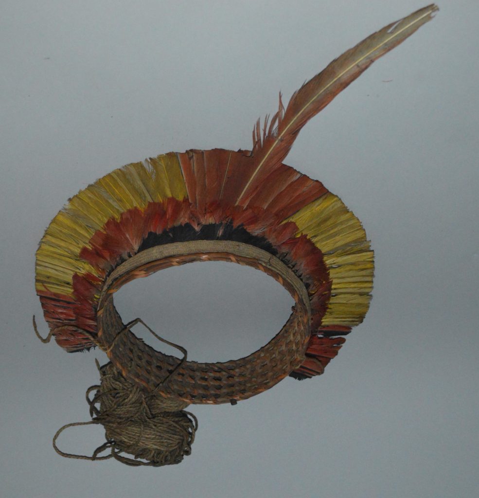 A headdress from Guyana made from reeds and yellow, red and black feathers that form a ring.